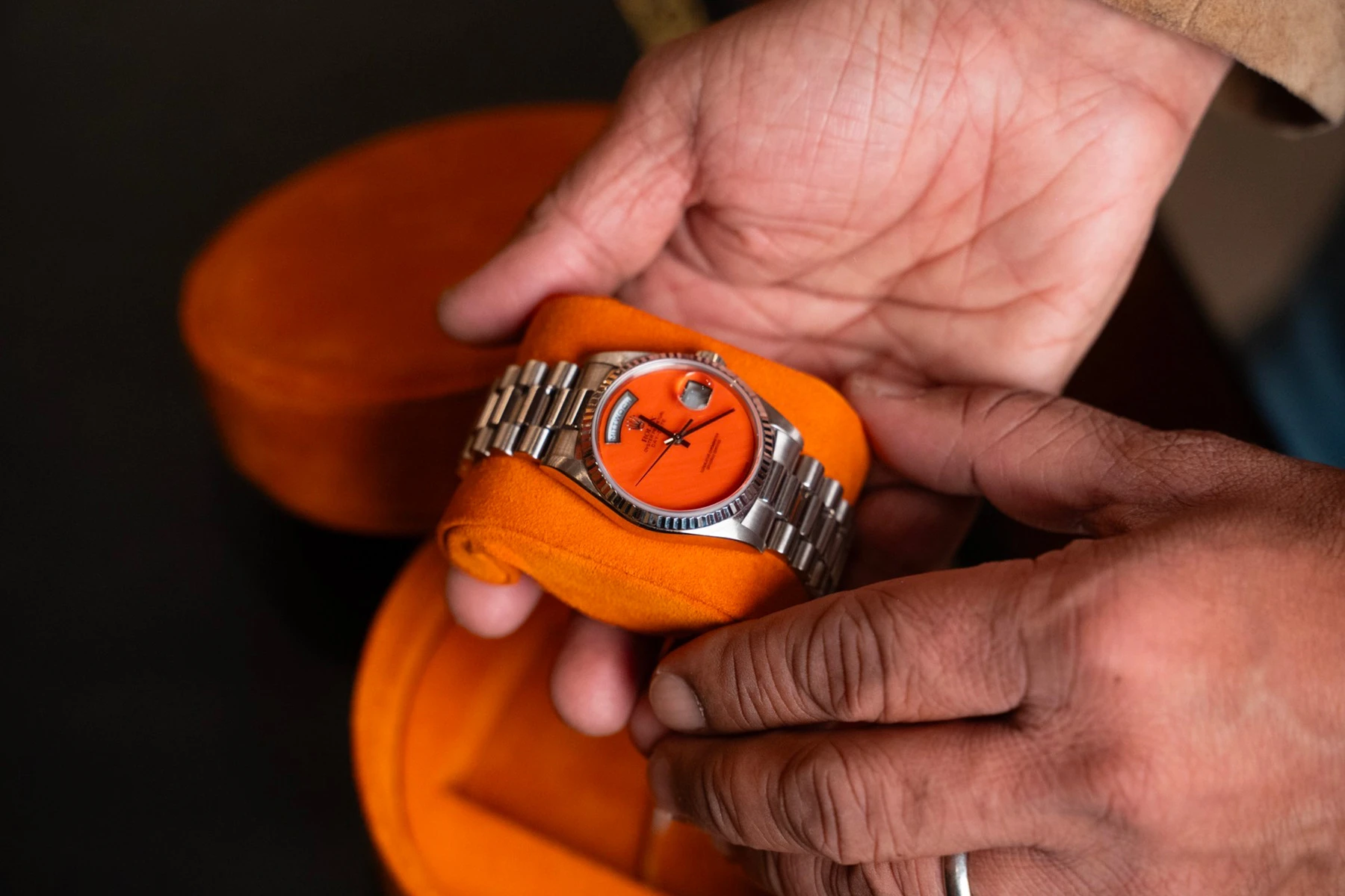 An orange dial Rolex Day-Date held in hand