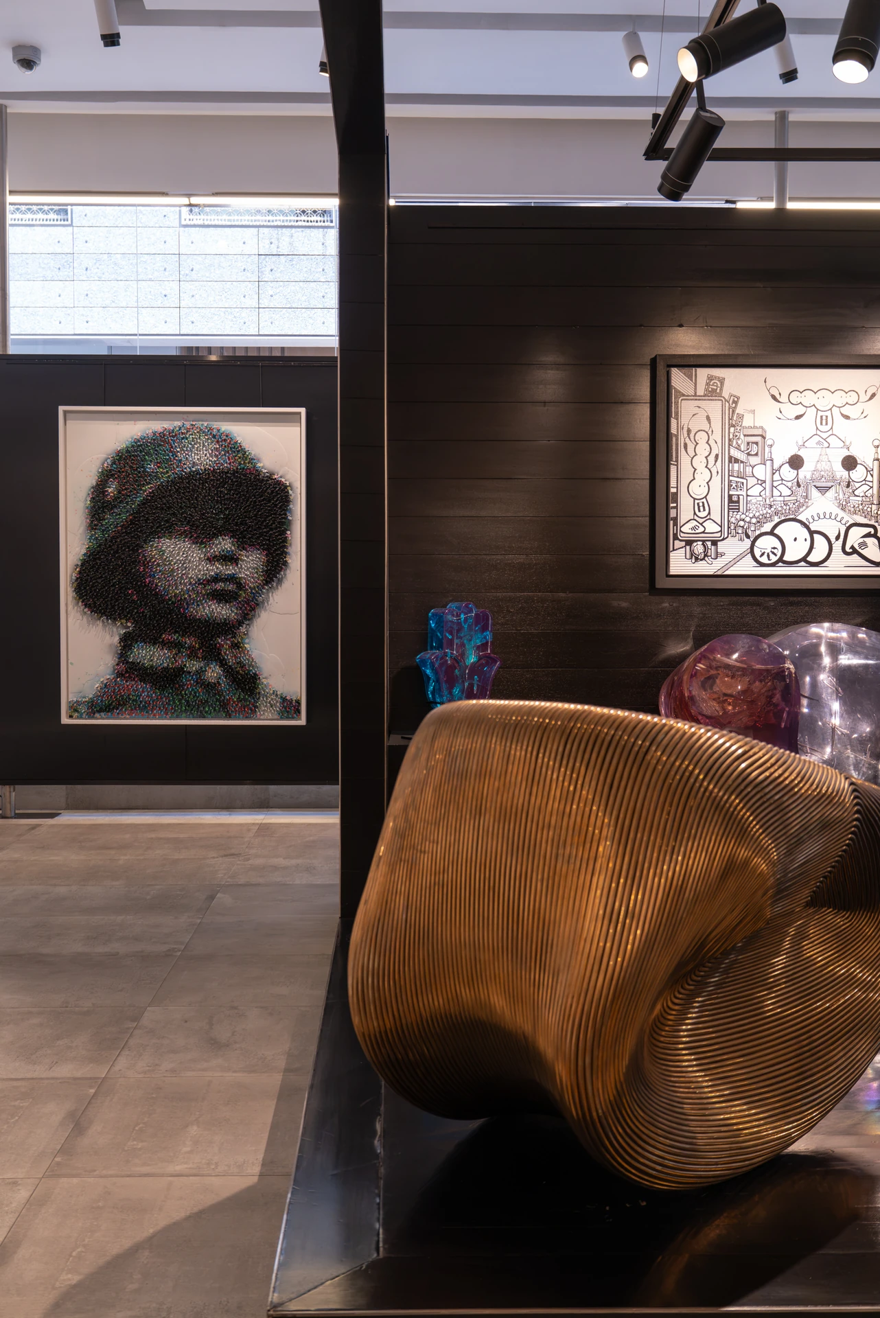 Black and white photography beside a carved wood sculpture at Opera Gallery DIFC